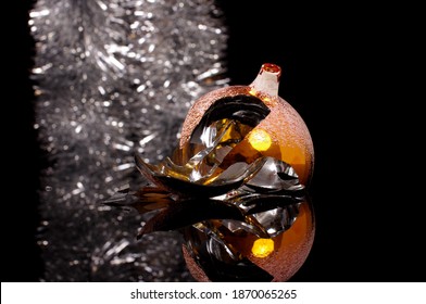 Broken Christmas Tree Decoration Ball Isolated On The Black Reflective Background