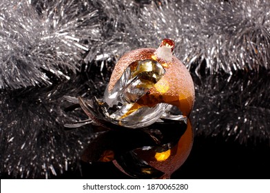 Broken Christmas Tree Decoration Ball Isolated On The Black Reflective Background