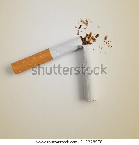 a broken cigarette on a beige background, symbolizing quitting smoking