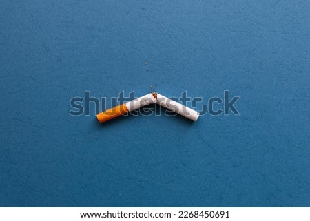 A broken cigarette with scattered tobacco for quit smoking concept. Broken cigarette on a blue background