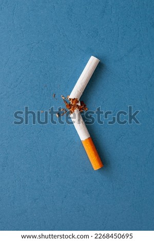 A broken cigarette with scattered tobacco for quit smoking concept. Broken cigarette on a blue background, top view