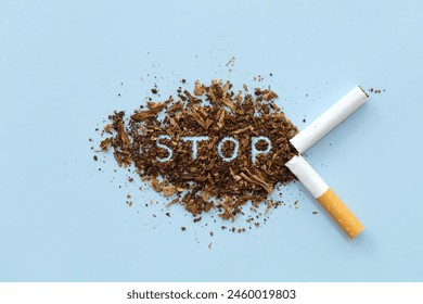 Broken cigarette scattered tobacco with text STOP on a light blue background. Quit smoking concept. stop smoking, World No Tobacco Day. say no. quit smoking for health. drugs, Lung Cancer, emphysema.