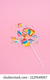 Broken Colorful Lollipop On Pastel Pink Background, Top View. Candy Colours. Minimal Sugar Detox, Junk Food And Party Concept.