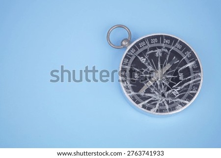 Broken compass on blue background. Copy space for text.
