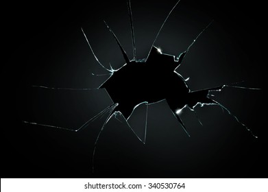 broken cracked glass with big hole over black background
