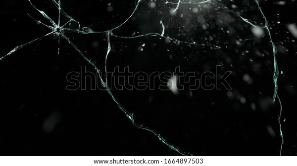 Broken cracks glass fracture effect texture\
isolated abstract black background. Bullet cracked window with big\
hole screen mirror weapon\
shot.