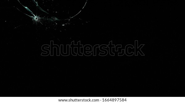 Broken cracks glass fracture effect texture\
isolated abstract black background. Bullet cracked window with big\
hole screen mirror weapon\
shot.
