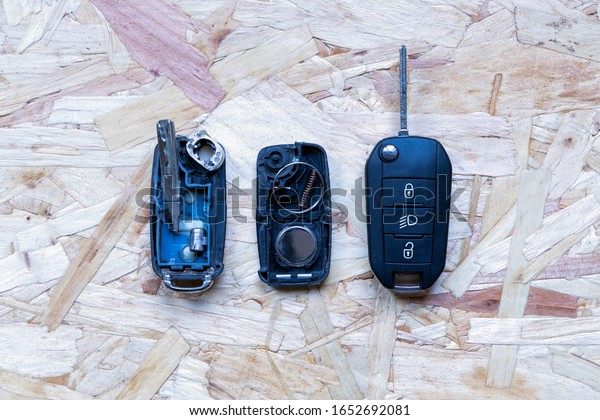 Broken or damaged\
remote key fob and new vehicle key on abstract wooden background.\
Broken or damaged remote key fob battery replacement of any vehicle\
car locksmith service.