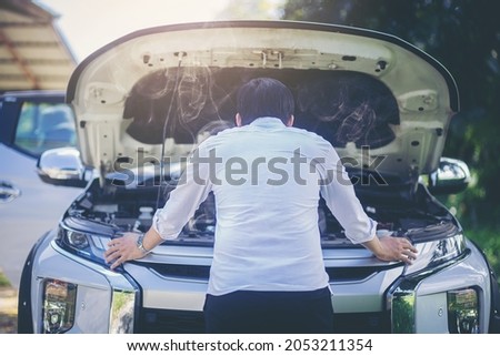 A broken down car, engine open and smoking, driver looking at the engine and do nothing. Selected focus