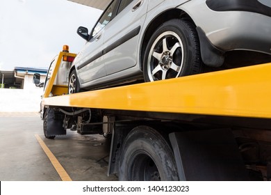 Broken Down Car On Flatbed Tow Truck Being Transported To Garage Workshop For Repair