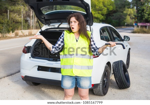 Broken down car. Woman\
standing alongside her broken down car on the road waiting for\
emergancy assistance