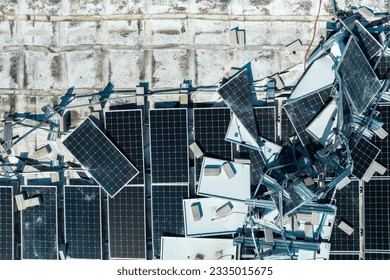 Broken down photovoltaic solar panels destroyed by hurricane Ian winds mounted on industrial building roof for producing green ecological electricity. Consequences of natural disaster