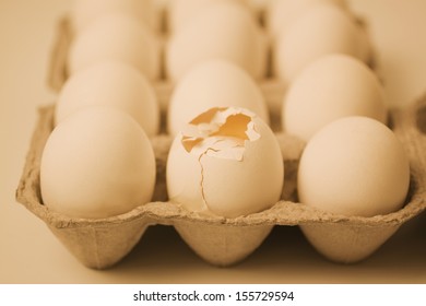 Broken Egg In A Carton With Other Eggs