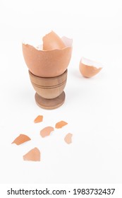 Broken Egg Shell In Old Wooden Eg Stand And Scattered Across White Surface. Minimalism. Animal Product Concept. Simple Breakfast. Sustainability Issue.