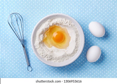 Broken Egg Yolk And Flour In A Bowl, Whisk And White Eggs On The Side. Food Preparation Concept. Baking Ingredients. Top View