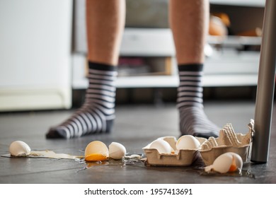 Broken eggs - accident at kitchen, mess. Legs on  background 
