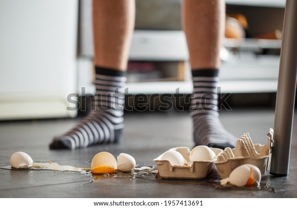 Broken eggs - accident at kitchen, mess. Legs on \
background 