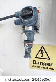 broken electric socket with danger electric shock risk poster on the white wall