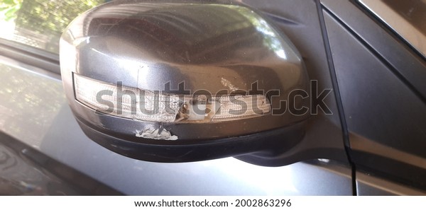 Broken electrical car mirror or car rear view due to\
an accident on the road