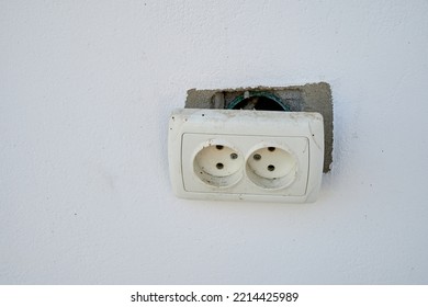 Broken electrical socket on a white wall..