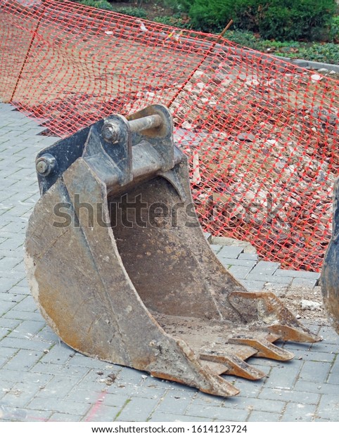 broken excavator bucket on the road near\
construction site