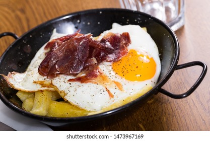Broken fried eggs with Iberico ham and fried potatoes