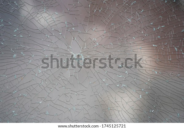 broken glass background. a glass window\
cracked with cobwebs. abstraction. Close-up of a cracked glass\
texture and background.