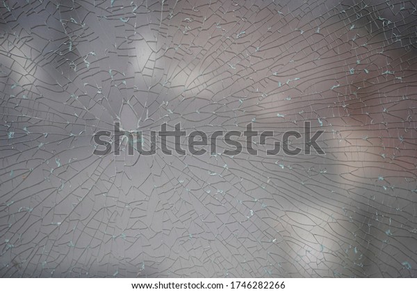 broken glass background. a glass window\
cracked with cobwebs. abstraction. Close-up of a cracked glass\
texture and background.