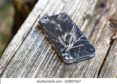 Broken glass of smart phone on the grunge wood. Copy space. Selective focus. Low depth of field.