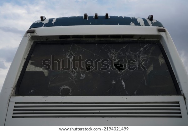 The broken glass windows of a bus in motion.\
Cracked glass, broken window. glass of the bus after the shelling\
of bandits or terrorists