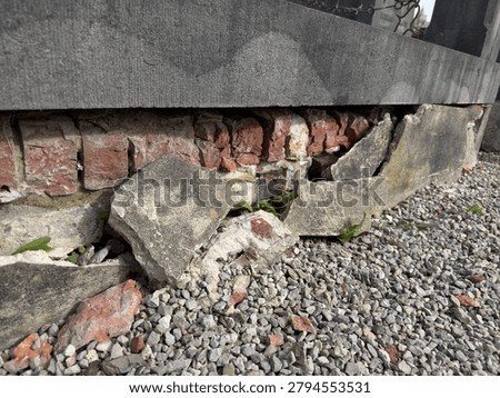 Broken grave foundation with exposed bricks and rubble in cemetery