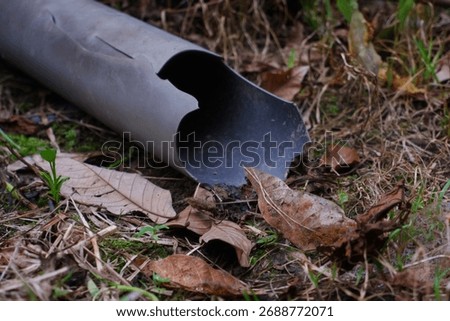 Broken Gray Plastic Pipe Lying in Dirt and Leaves