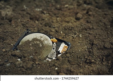 Broken Hard Drives on the soil ground without cover showing inside part. An illustration concept of data security, un-safe data hard drives disposal