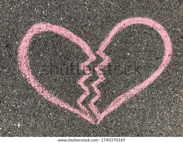 Broken heart divided in to two parts hand drawn\
with red sidewalk chalk on the grey asphalt, symbol of end of love,\
concept of break up and divorce\
