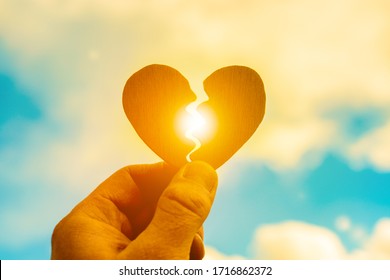 Broken heart in a man’s hand on a sunset background. Parting, stop loving, break your heart. Divorce - Shutterstock ID 1716862372
