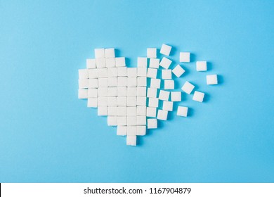 The broken heart made of cubes of sugar on a blue background