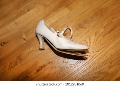 Broken High Heel White Shoe On Wooden Background