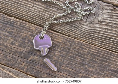 Broken House Key On Chain On Wooden Background 
