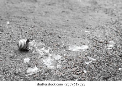 Broken light bulb and it's glass fragments lying on ground, Shattered incandescent lamp with broken glass fragments, symbolizing destruction and damage - Powered by Shutterstock