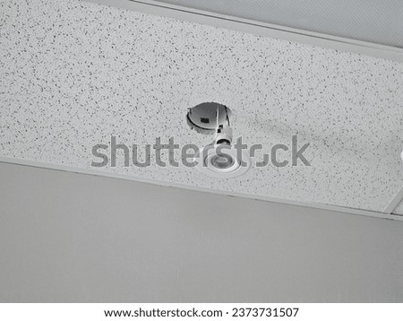 A broken light hanging from a hole in a ceiling with the wires exposed.