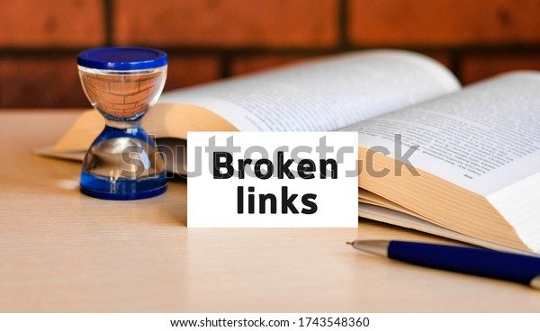 Broken links seo - business\
concept text on a white background with a hourglass and an open\
book
