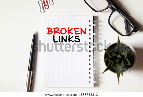 Broken links -\
text on yellow note sheets on a dark wooden background with\
crumpled sheets and a magnifying\
glass