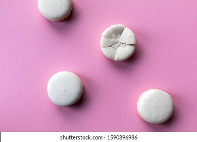 Broken macaroon cake compared to other unbroken on the pink background. The concept of non-ideality, identity; loss and broken soul