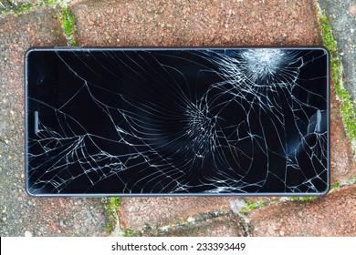 Broken mobile phone (crashed display) lying on pavement