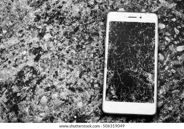Broken\
mobile screen on the road or concrete\
floor.