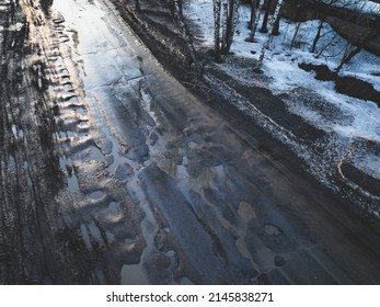 Broken old asphalt road outside the city. Pits and potholes. Aerial view