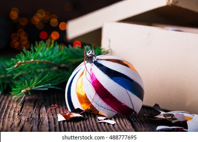 Broken old vintage Christmas balls on wooden table. Christmas lights and Christmas tree. Box with Christmas balls.