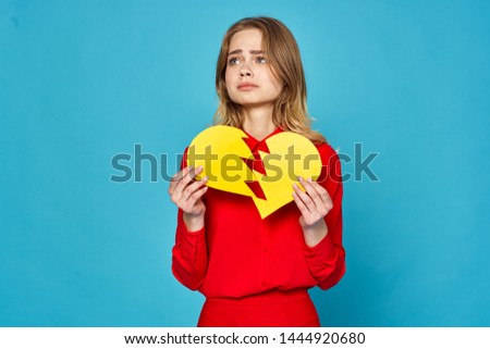 Broken paper heart in woman's hands on blue background                     