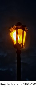 Broken Park Lamp Post Shining Against The Gloomy Night Sky