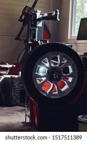 Broken Part Of Car With Wheel At Busy Auto Service Workshop Near Window.